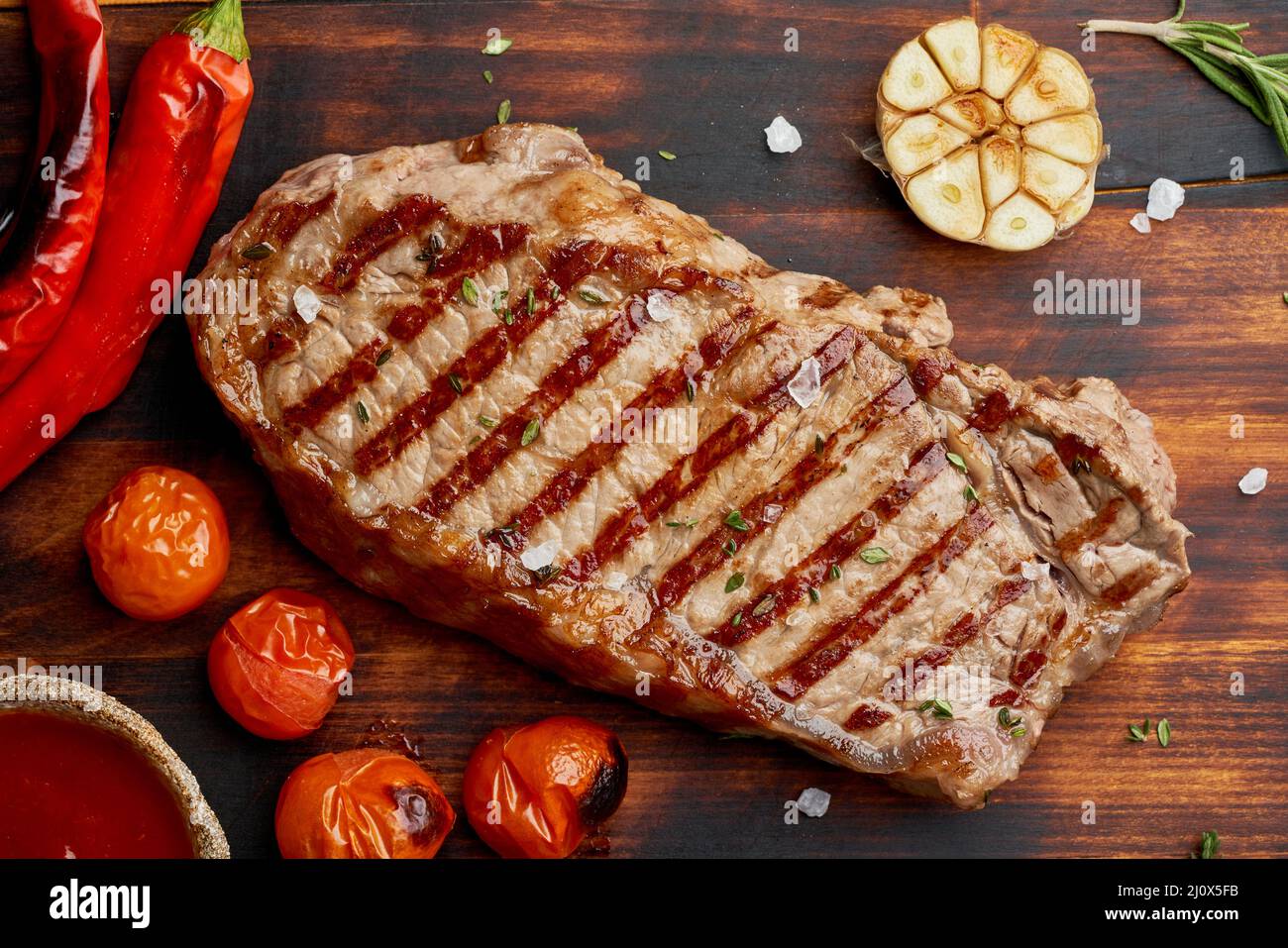 Bistecca di manzo intera, striploin fritto su tagliere di legno. Dieta chetogenica del cheto. Primo piano, vista dall'alto Foto Stock
