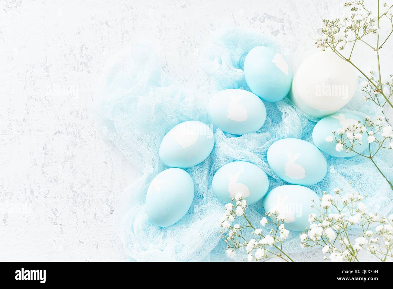 Pasqua. Vacanze. Sfondo bianco chiaro, delicati colori pastello. Uova blu con immagine di coniglio Foto Stock