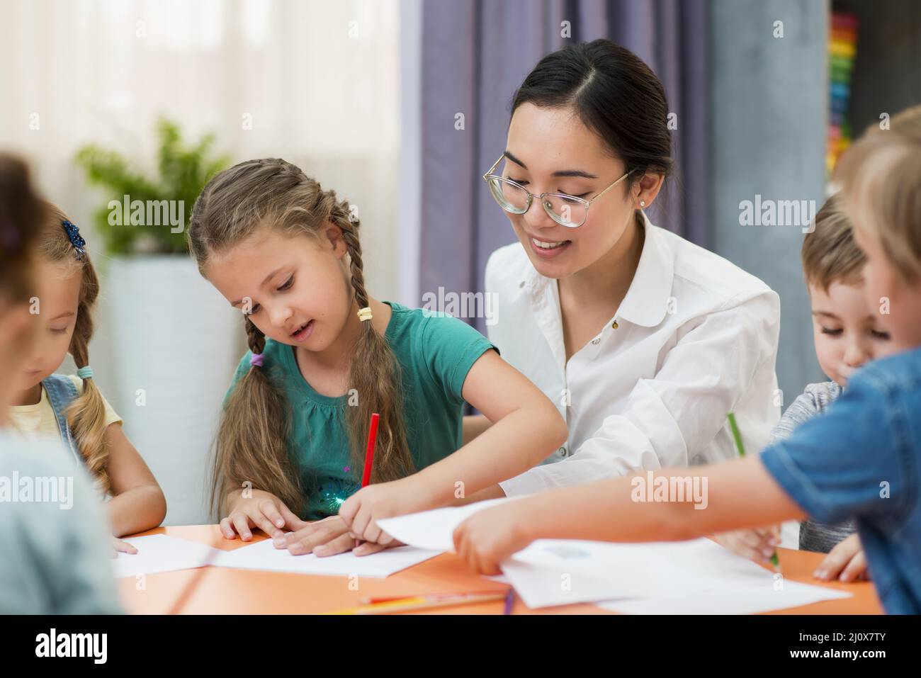 Giovane insegnante che aiuta i suoi studenti. Foto di alta qualità Foto Stock