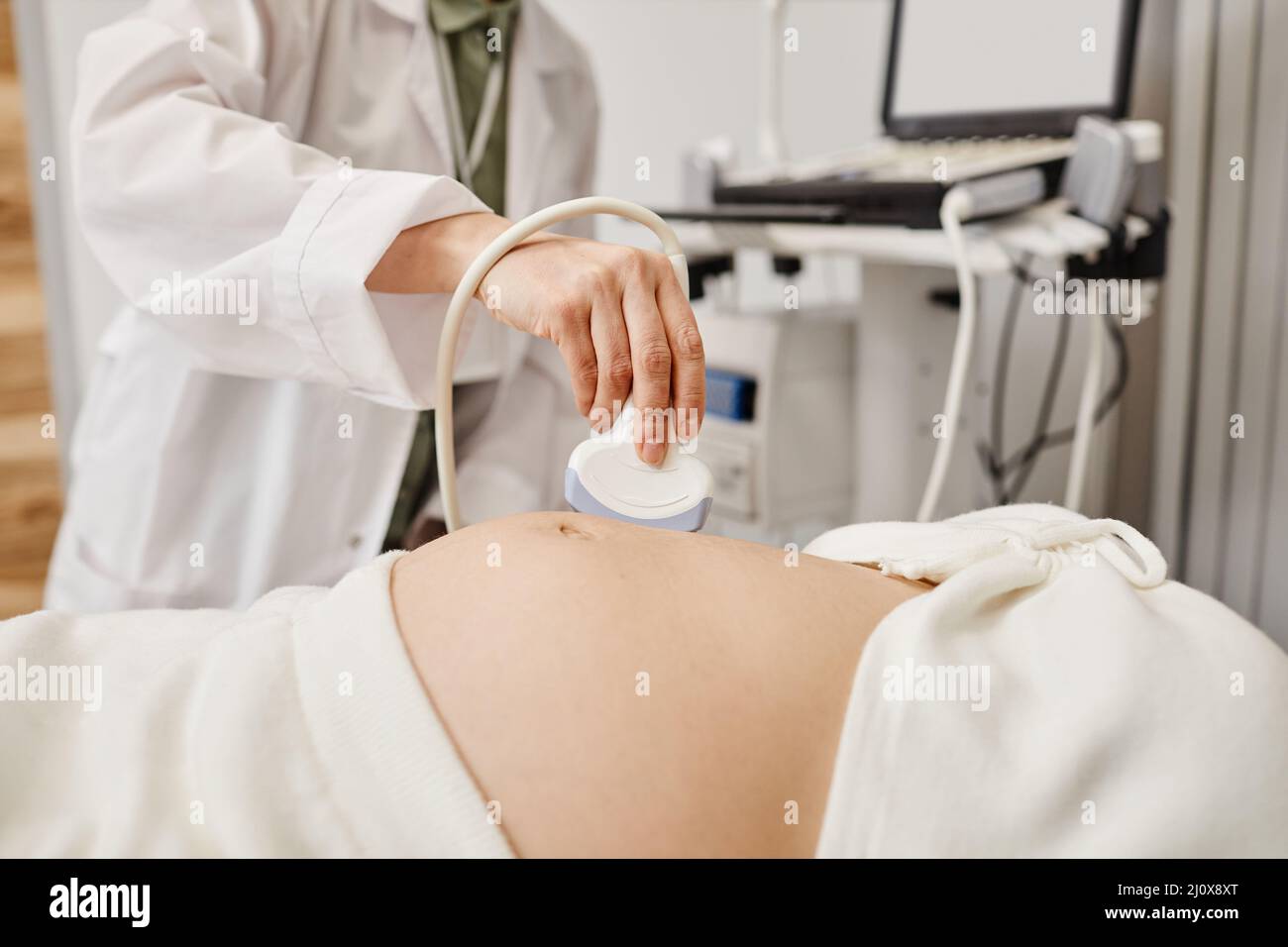 Primo piano dell'esame ecografico di una donna incinta con particolare attenzione al medico che tiene il trasduttore alla pancia, spazio di copia Foto Stock