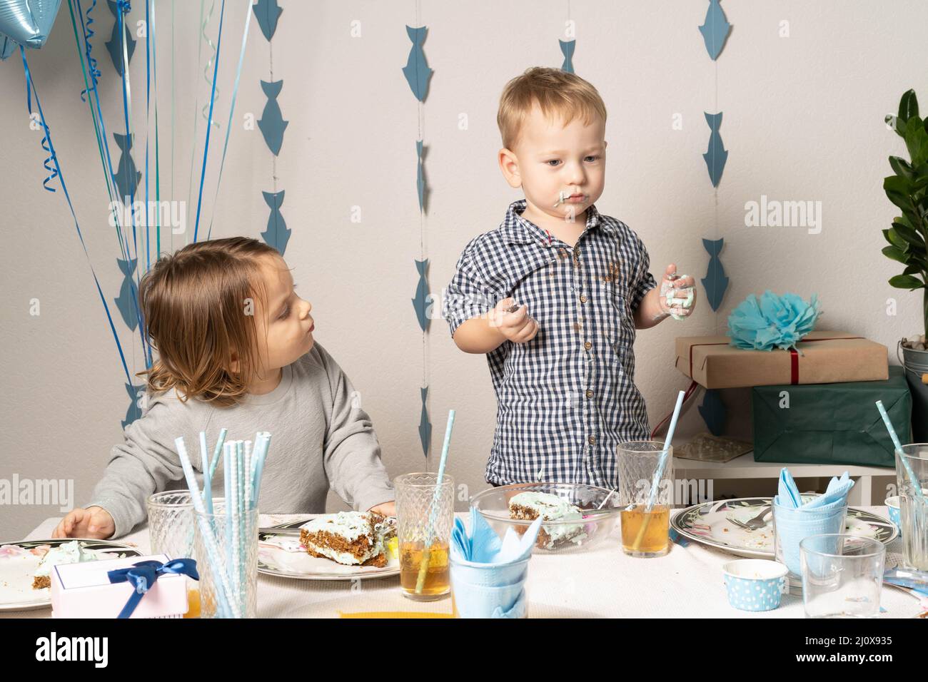 Fratelli. Compleanno del ragazzo al tavolo. I ragazzi al tavolo tagliano una torta di compleanno. Foto Stock