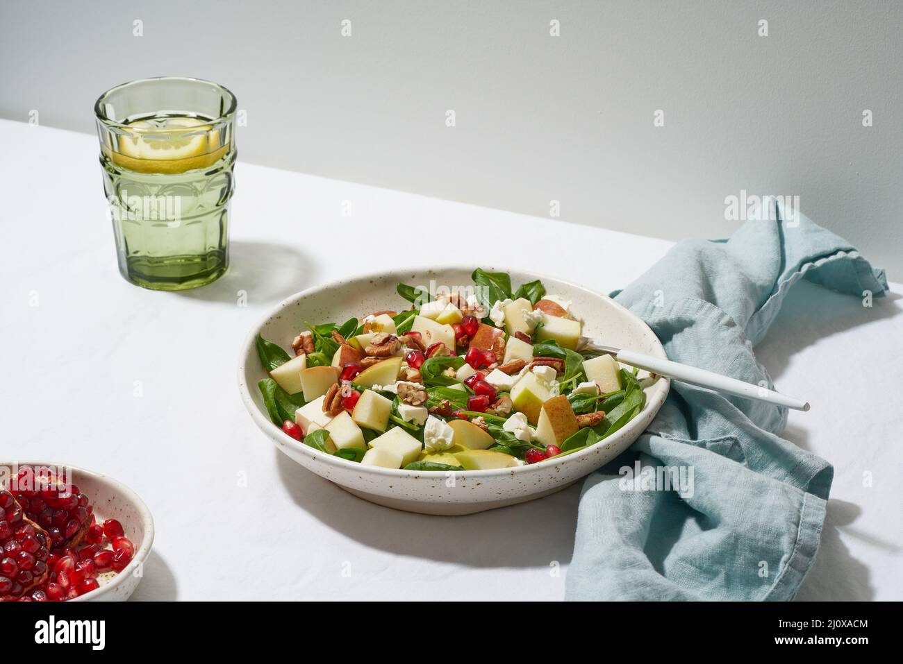 Insalata con noci. Spinaci con mele, noci pecan e feta. Luce dura, ombre, vista laterale Foto Stock