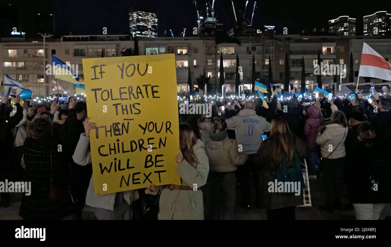 Tel Aviv, Israele. 20th Mar 2022. Le persone hanno un segnale da dimostranti che accendono le luci del telefono per un minuto di silenzio in memoria delle vittime della guerra ucraine, mentre si riuniscono per guardare un video discorso del presidente ucraino Volodymyr Zelensky al parlamento israeliano trasmesso in piazza Habima il 20 marzo 2022 a Tel Aviv, Israele. Zelensky ha chiesto ad Israele di imporre sanzioni alla Russia e di aiutare l'Ucraina, ricordando la Germania nazista e confrontando le sue azioni con la situazione attuale. Credit: Eddie Gerald/Alamy Live News Foto Stock