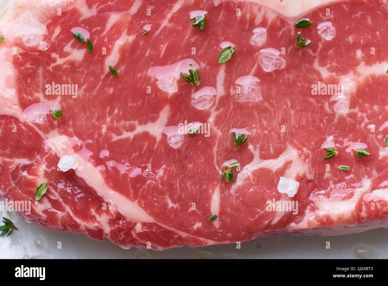 Grande pezzo intero di carne di manzo cruda, striploin. Bistecca con condimento, primo piano, macro Foto Stock