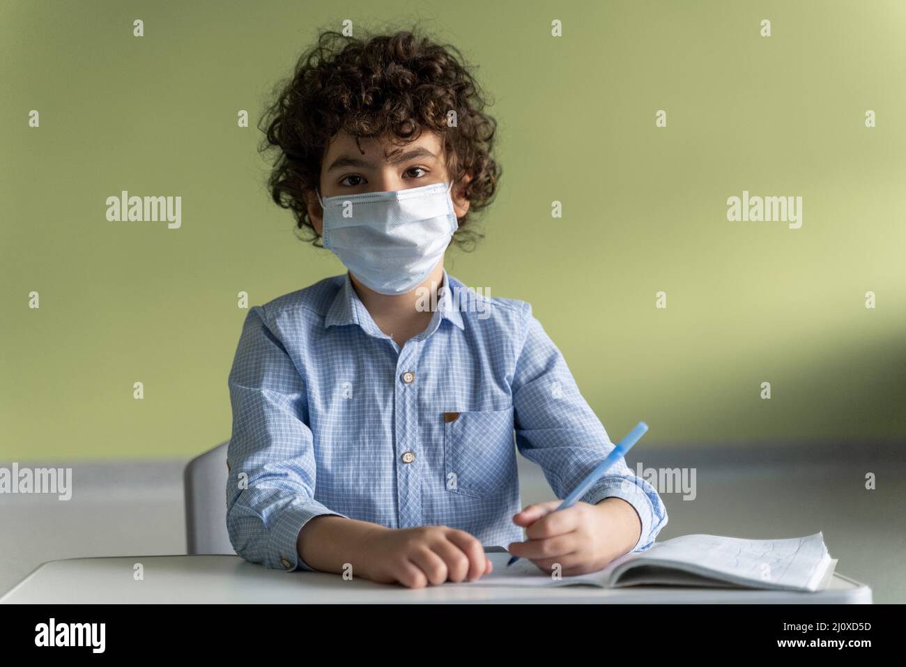 Vista frontale ragazzo con maschera medica scuola durante pandemia Foto Stock