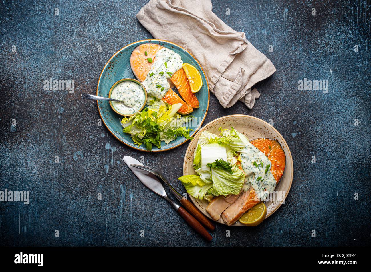 Pasto sano bistecche di salmone alla griglia con salsa all'aneto e foglie di insalata su due piatti Foto Stock