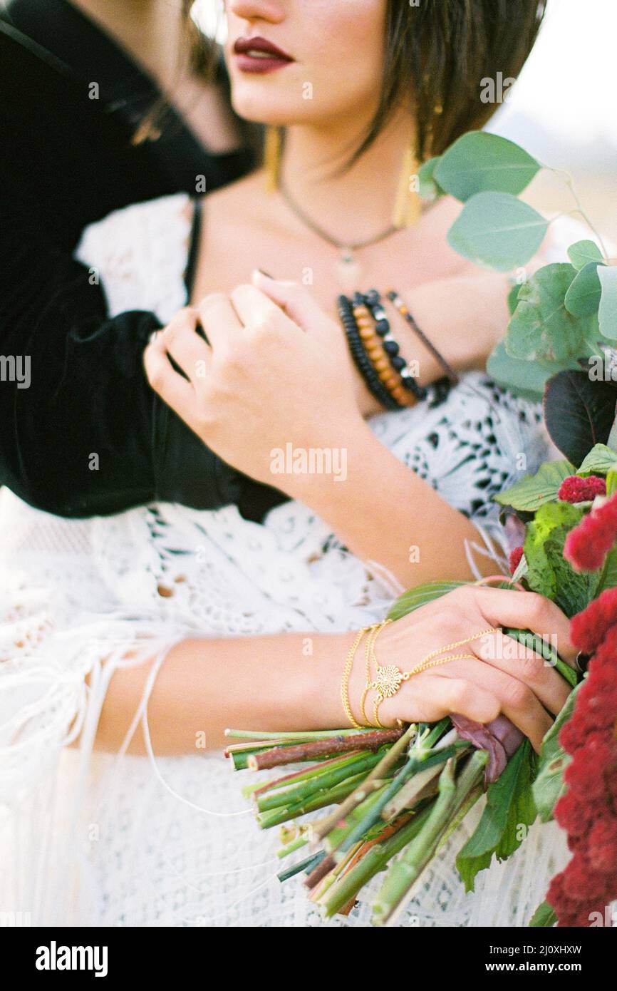 Sposare abbracci da dietro sposa con un bouquet di fiori. Verticale Foto Stock