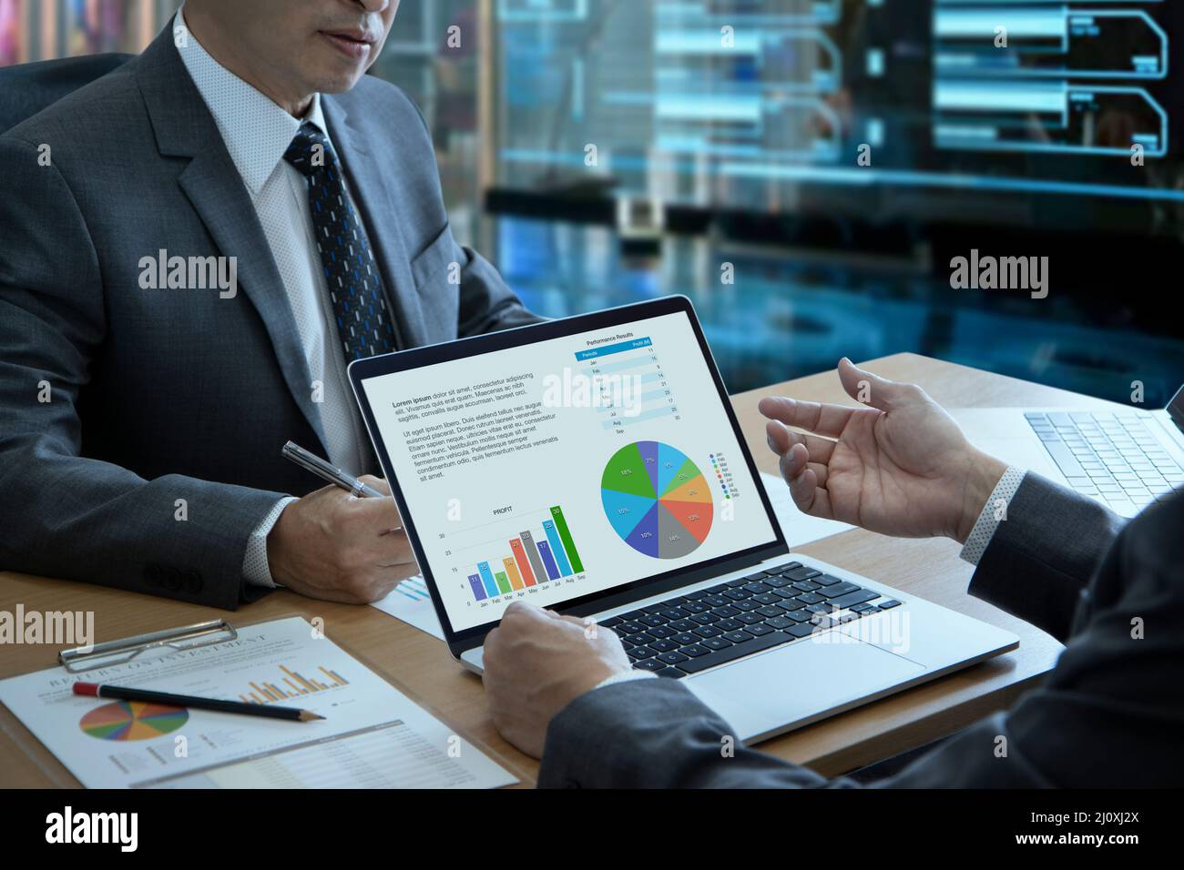 Due uomini d'affari con notebook in un ufficio moderno che analizzano le informazioni aziendali sulle prestazioni aziendali e sul ritorno sugli investimenti Foto Stock
