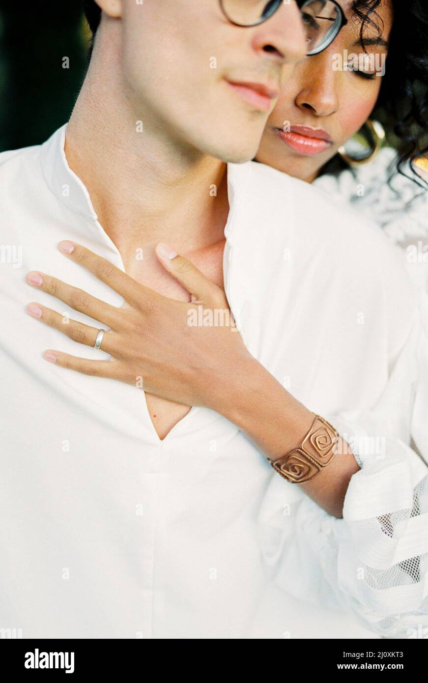 Donna in abito bianco abbraccia un uomo da dietro. Verticale Foto Stock Donna in abito bianco abbraccia un uomo da dietro. Verticale Foto Stock