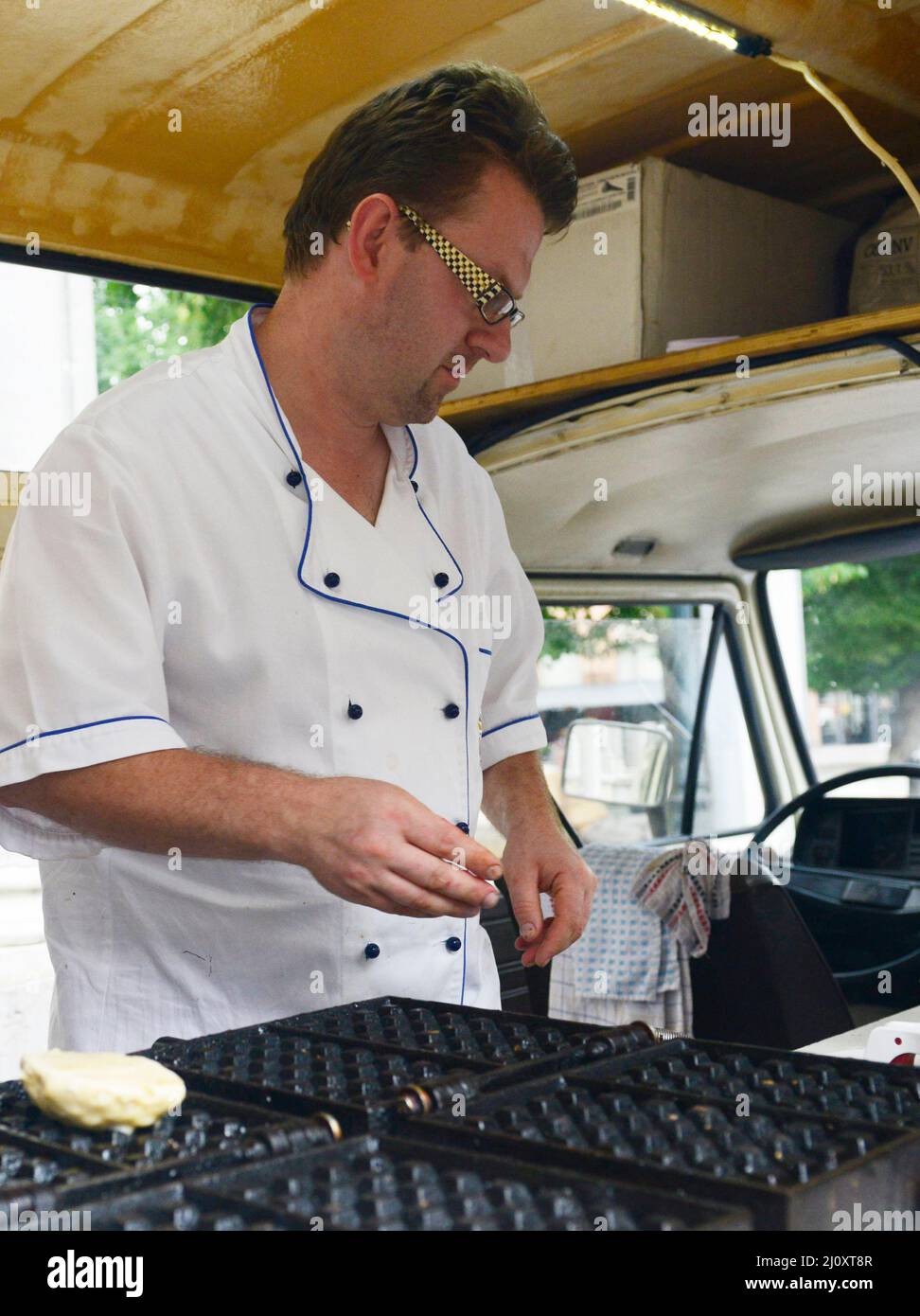 Uno chef di dessert prepara waffle belgi a Bruges, Belgio. Foto Stock