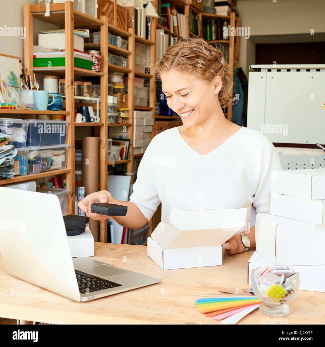 Felice proprietario di affari locali. Donna imprenditore che raccoglie e impacchettano regali Foto Stock