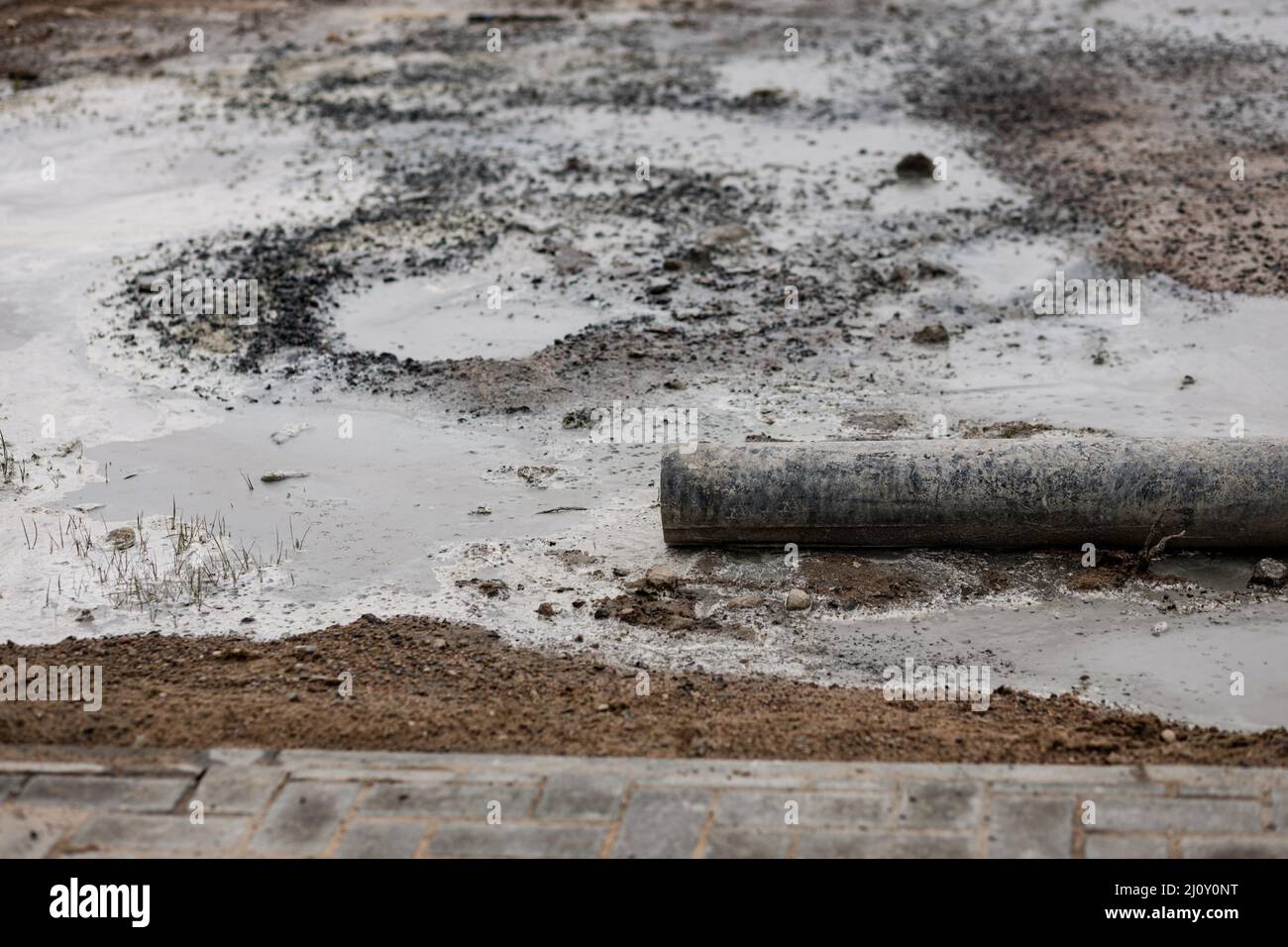Vecchio tubo rotto arrugginito (tubo) contro terra scura e con un pudddle di acqua sporca in antistante. Inquinamento di suolo Foto Stock