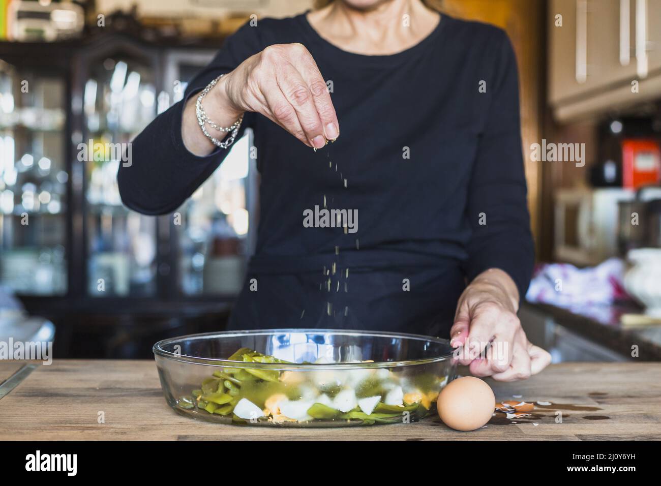 Crop mani anziana donna cospargere sale piatto. Foto di alta qualità Foto Stock