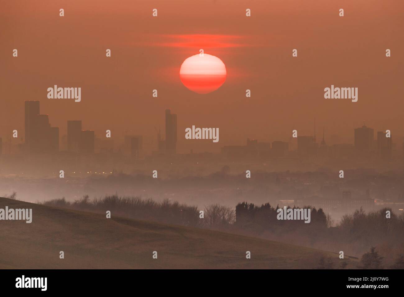 Il sole tramonta dietro la città di Manchester sull'equinozio Vernal, il primo giorno astronomico di primavera Foto Stock