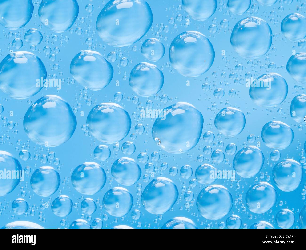 Abstract sfondo blu con piccoli e grandi convessa sferica di gocce di acqua sul vetro. Bolle sulla finestra. Macro close up. Foto Stock
