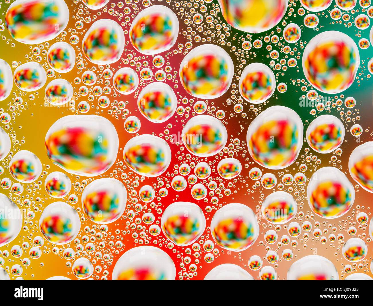Abstract colorato sfondo vivace con piccoli e grandi convessa sferica di gocce di acqua sul vetro. Macro, vista dall'alto, vicino. Foto Stock