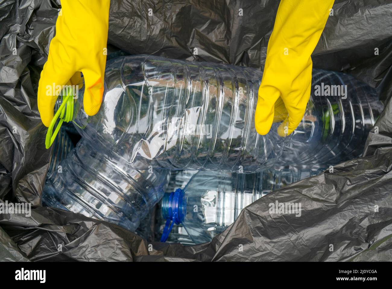 Gli uomini nel cestino di raccolta. Mani mettendo una bottiglia di plastica in un cestino di plastica in borsa. Foto Stock