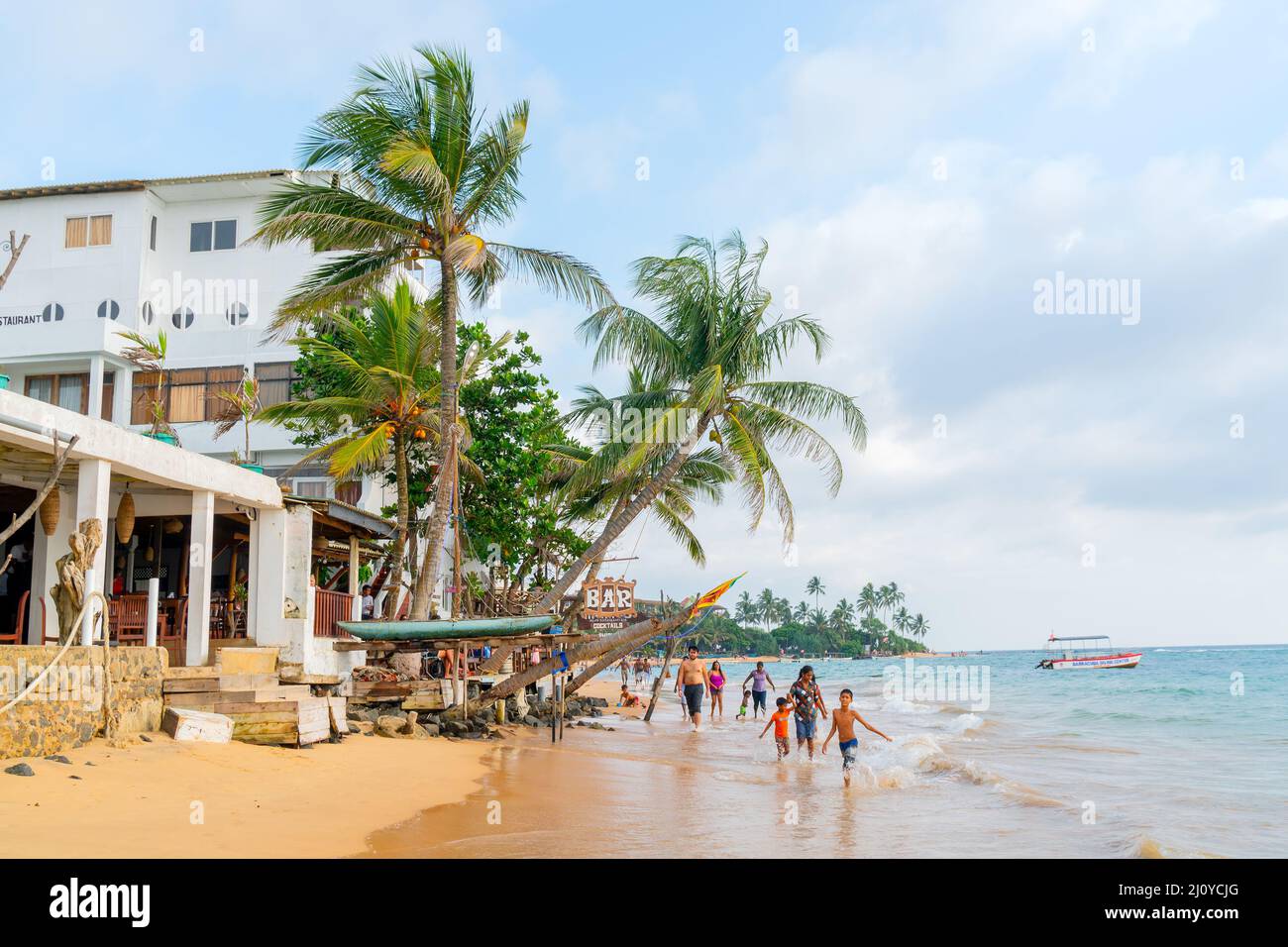 Hikkaduwa, Sri Lanka. Marzo 1, 2018. Turisti sulla spiaggia sullo sfondo dell'hotel. Foto Stock