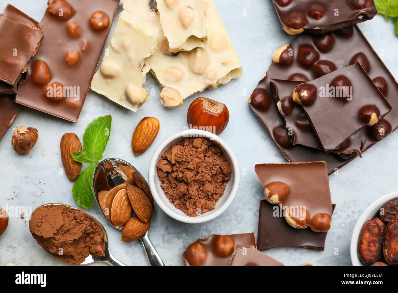 Pezzi di gustoso cioccolato con noci e cacao in polvere su sfondo colorato Foto Stock
