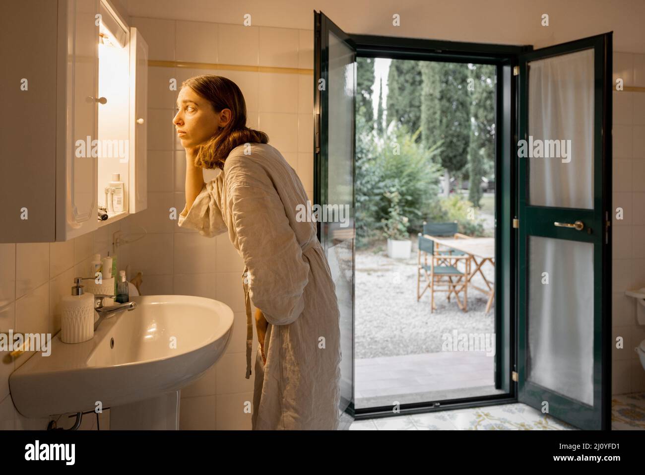 Ragazza asciugando i capelli in bagno della camera d'albergo al mattino Foto Stock