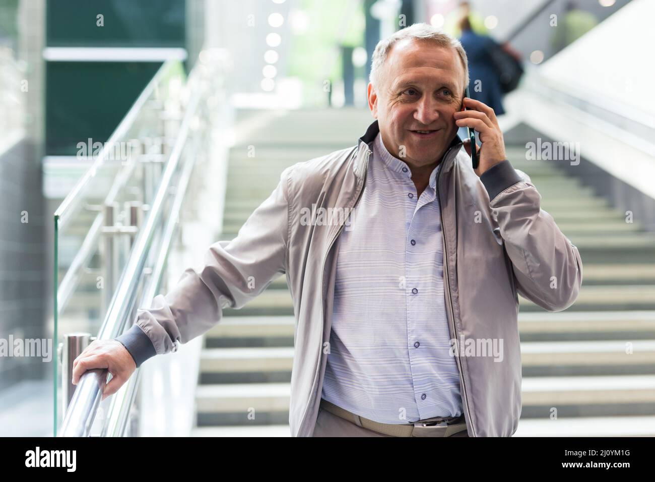 Uomo di mezza età con telefono che scende le scale nel centro commerciale Foto Stock
