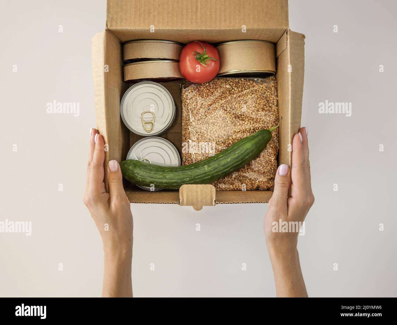Flat Lay mano che tiene la scatola cibo donazione. Foto di alta qualità Foto Stock