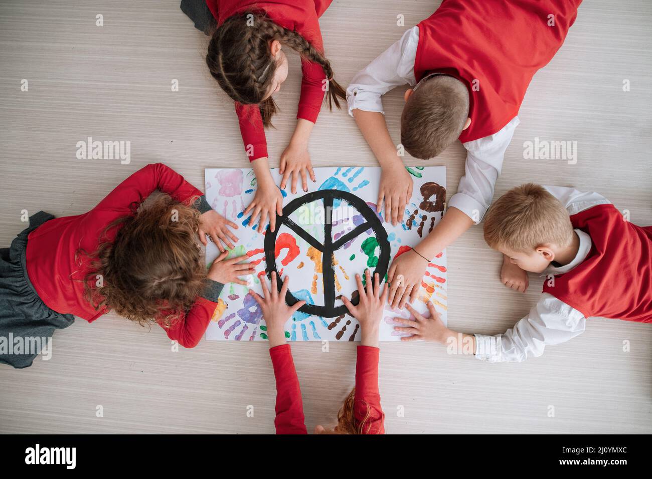 Vista dall'alto dei bambini che fanno un poster di segno di pace a scuola. Foto Stock