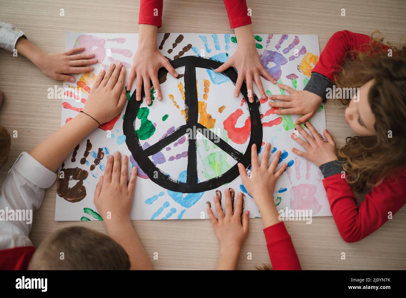Vista dall'alto dei bambini che fanno un poster di segno di pace a scuola. Foto Stock