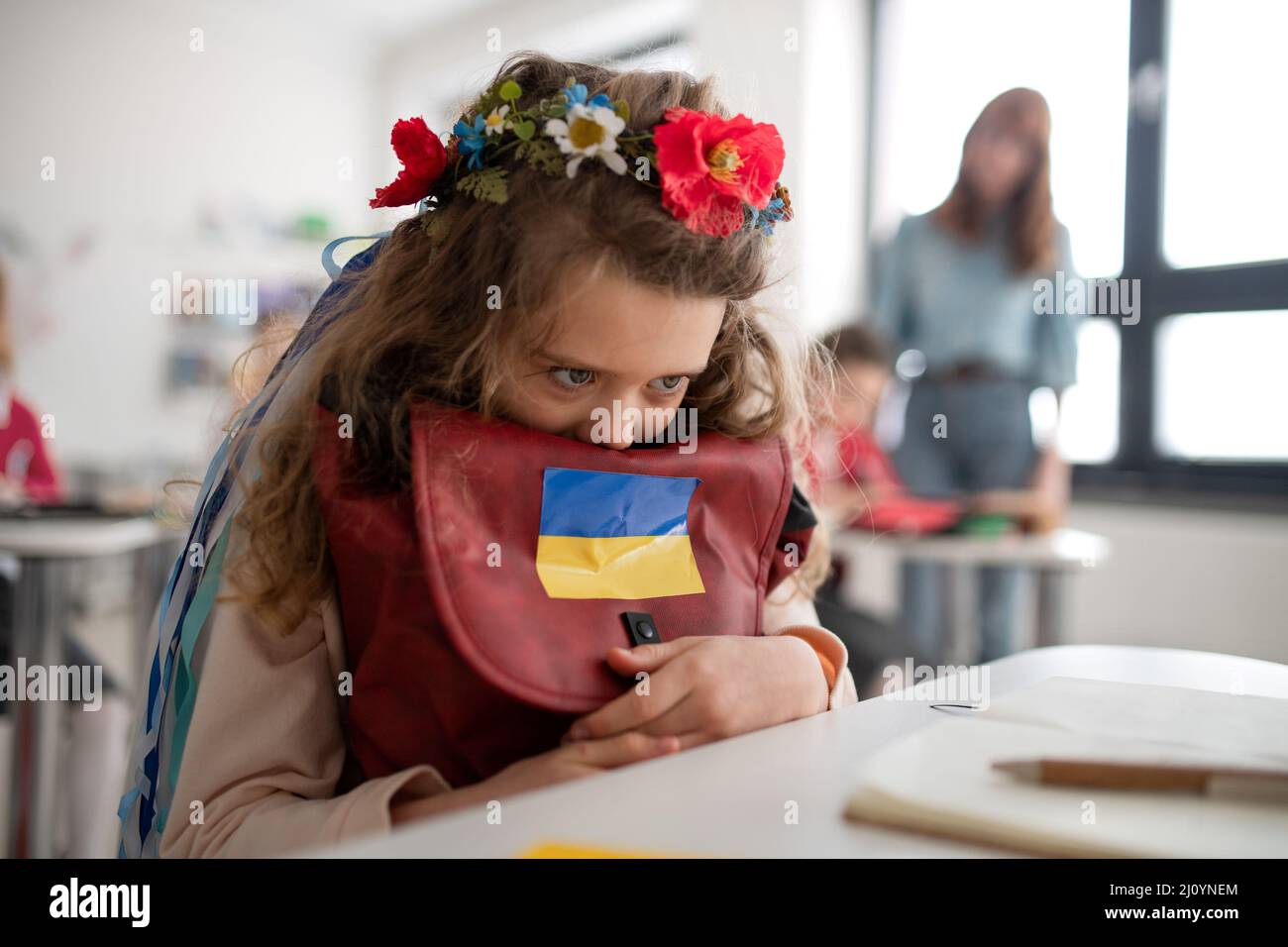 Piccola ragazza Ucraina triste seduta a scuola, concetto di iscrizione dei bambini ucraini alle scuole. Foto Stock