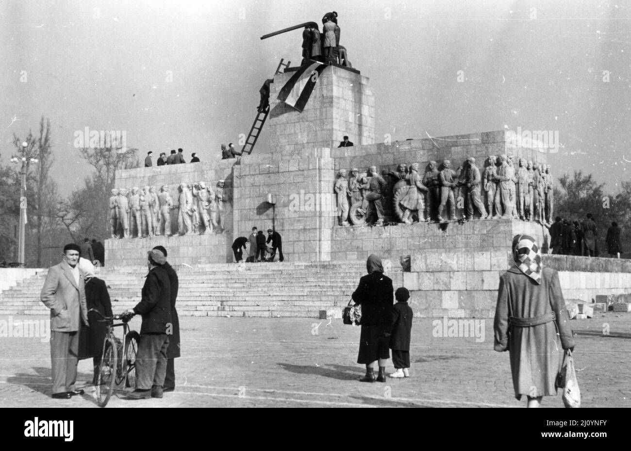 A Budapest durante la Rivoluzione Ungherese del 1956, gli anti-comunisti e i nazionalisti collocano una bandiera nazionale ungherese sulla cima di una statua demolita di Josef Stalin. Foto Stock