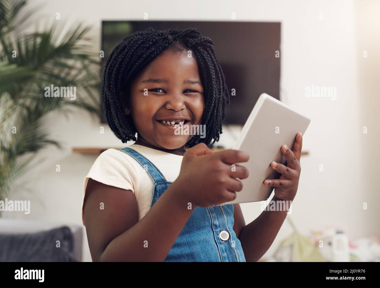 Questo ha tutto l'intrattenimento di cui ho bisogno. Ritratto di una bambina adorabile che si diverte mentre si usa un tablet digitale a casa. Foto Stock