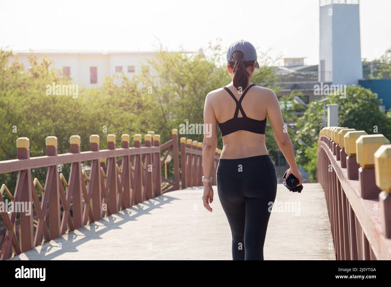 Vista posteriore di donna esercizio a piedi sul ponte nel parco della città. Foto Stock
