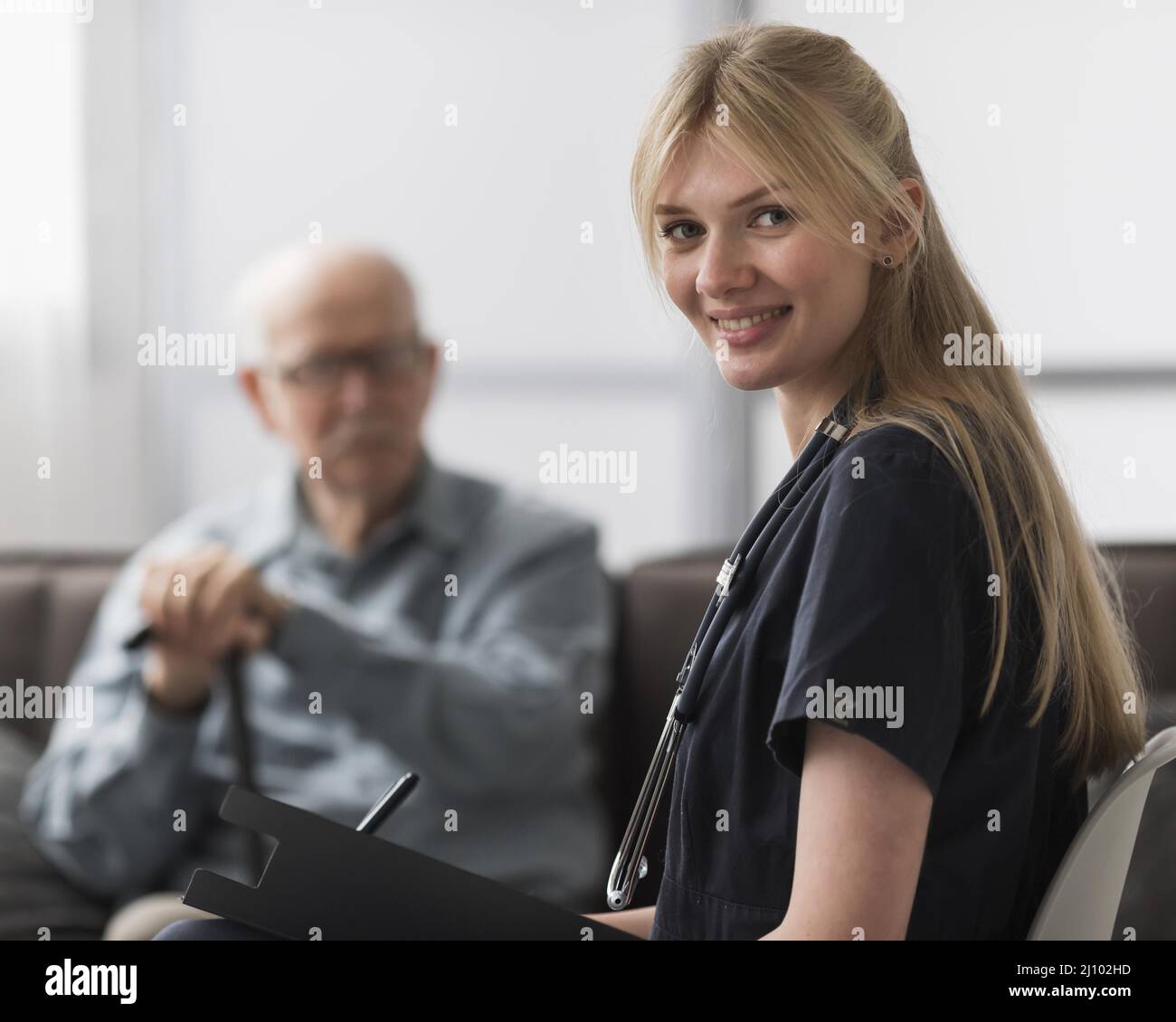 Infermiera donna sorridente in posa con l'uomo che allatta a casa Foto Stock