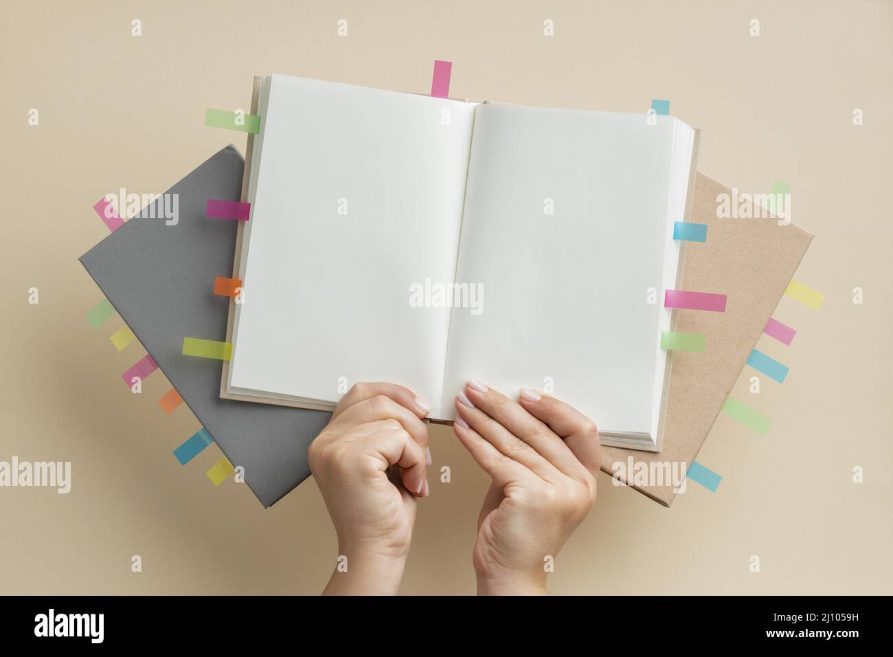 Persona che tiene libri con adesivi colorati per promemoria Foto Stock