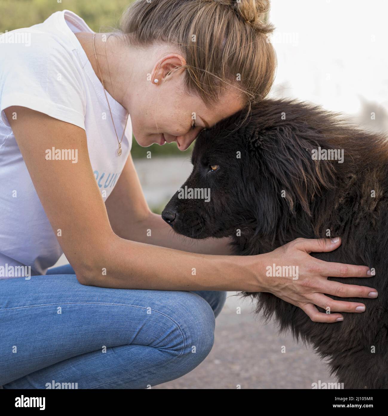 Vista laterale donna con morbido cane nero all'aperto Foto Stock