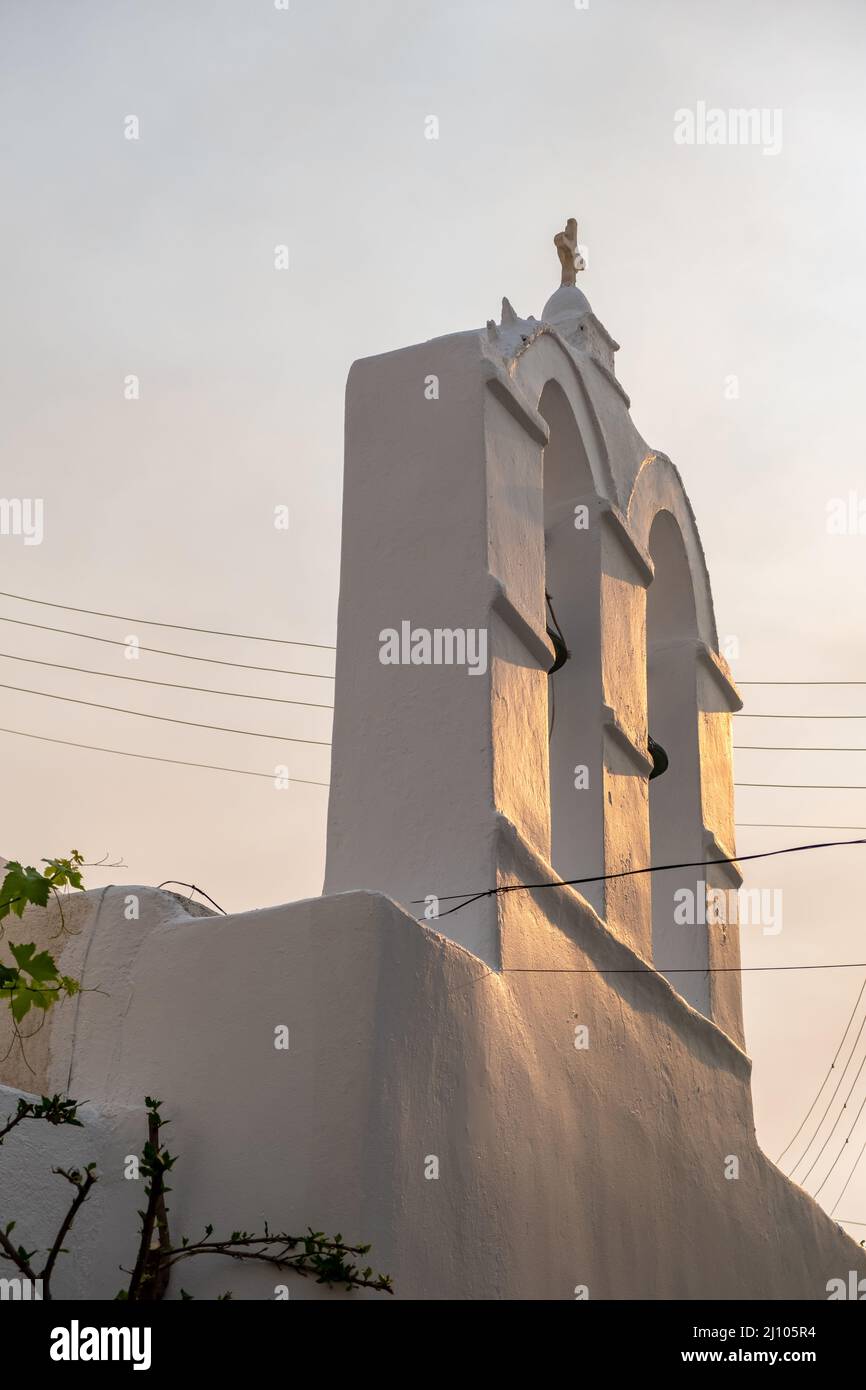 Religione ortodossa cappella di colore bianco campanile. Piccolo campanile della chiesa su sfondo cielo, vista ad angolo basso. Isola greca. Grecia. Foto Stock