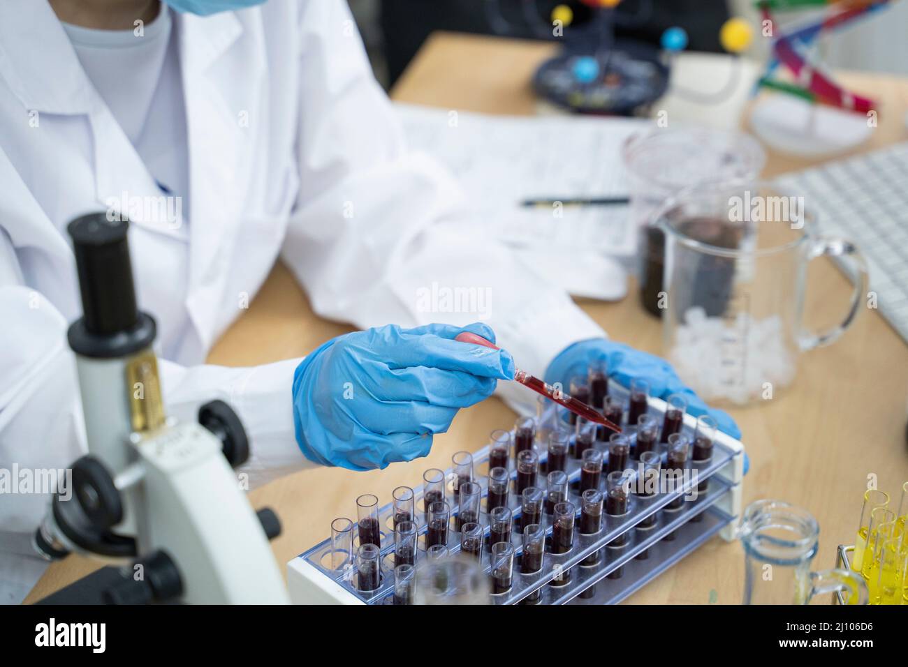 Una mano del medico preleva una provetta per campioni di sangue dallo scaffale in cui si trova l'analizzatore. Foto Stock