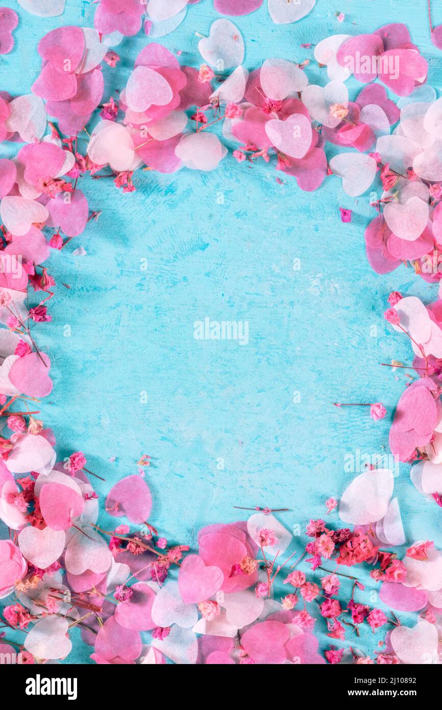 Biglietto di auguri di San Valentino o sfondo di invito al matrimonio con cuori di carta rosa e fiori di rosa confetti, un modello di design su sfondo blu Foto Stock