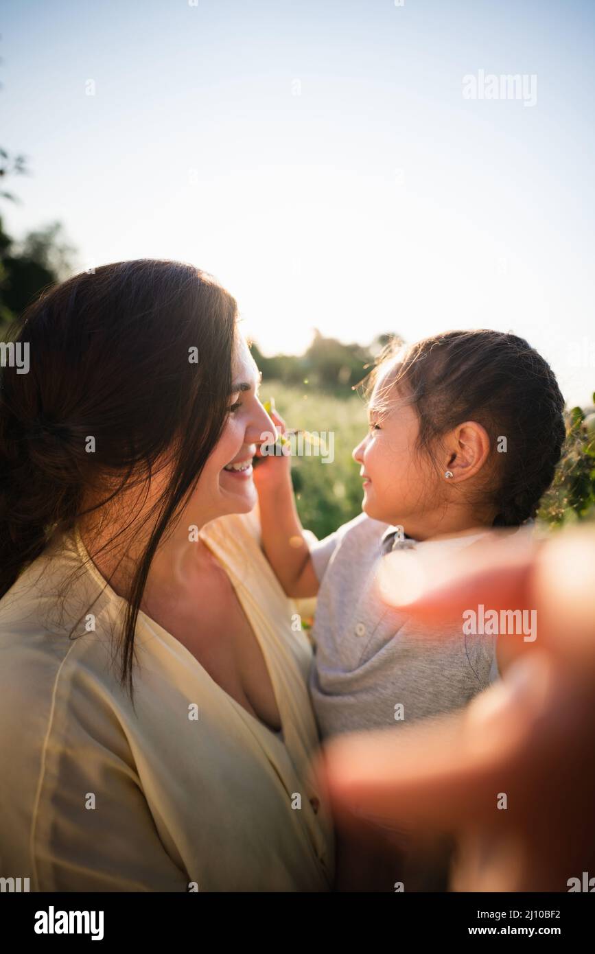 Madre europea e sua figlia asiatica nel giardino delle mele in estate Foto Stock