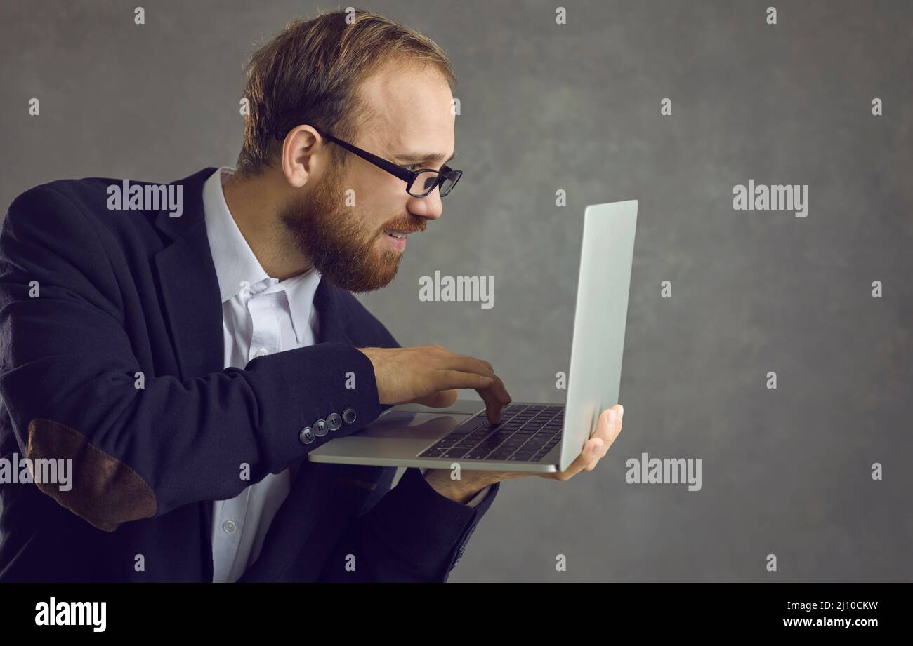 Un uomo sta digitando sulla vista laterale di un computer portatile. Foto Stock