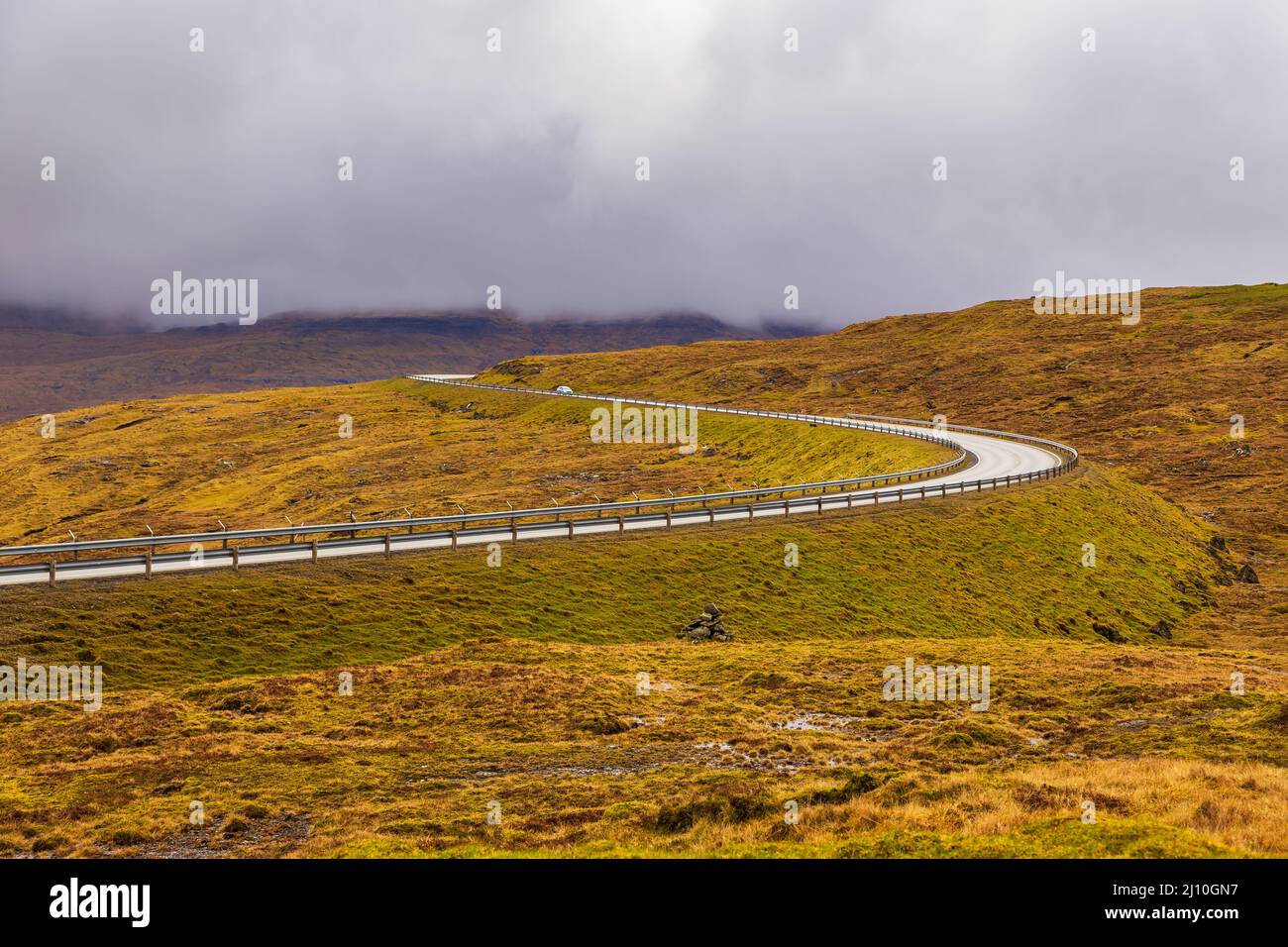Strada asfaltata lungo le colline dell'isola di Streymoy. Giorno nuvoloso. Isole Faroe, Danimarca. Foto Stock