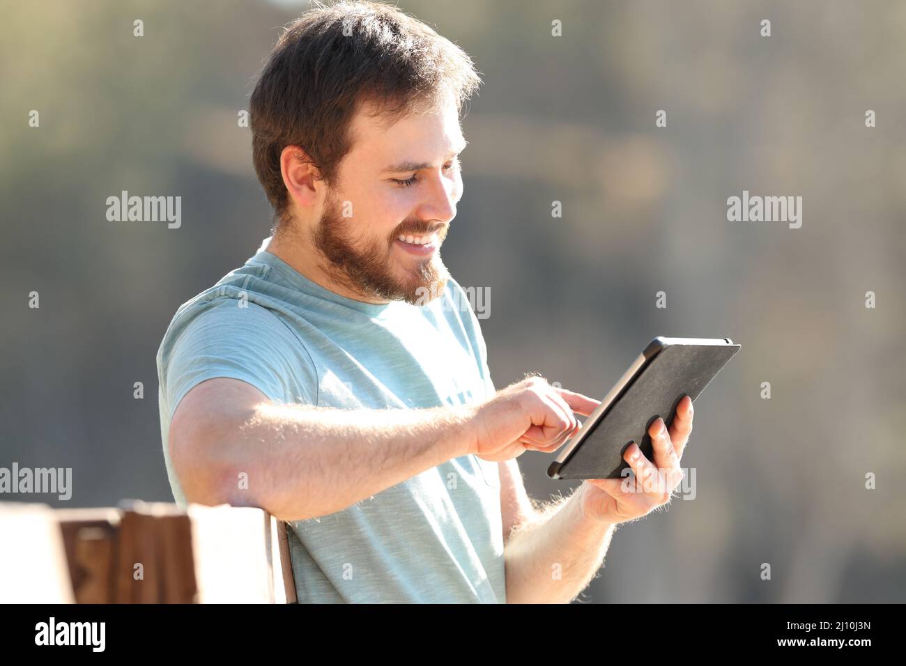 Uomo felice di controllare i contenuti dei tablet online all'aperto una giornata di sole Foto Stock