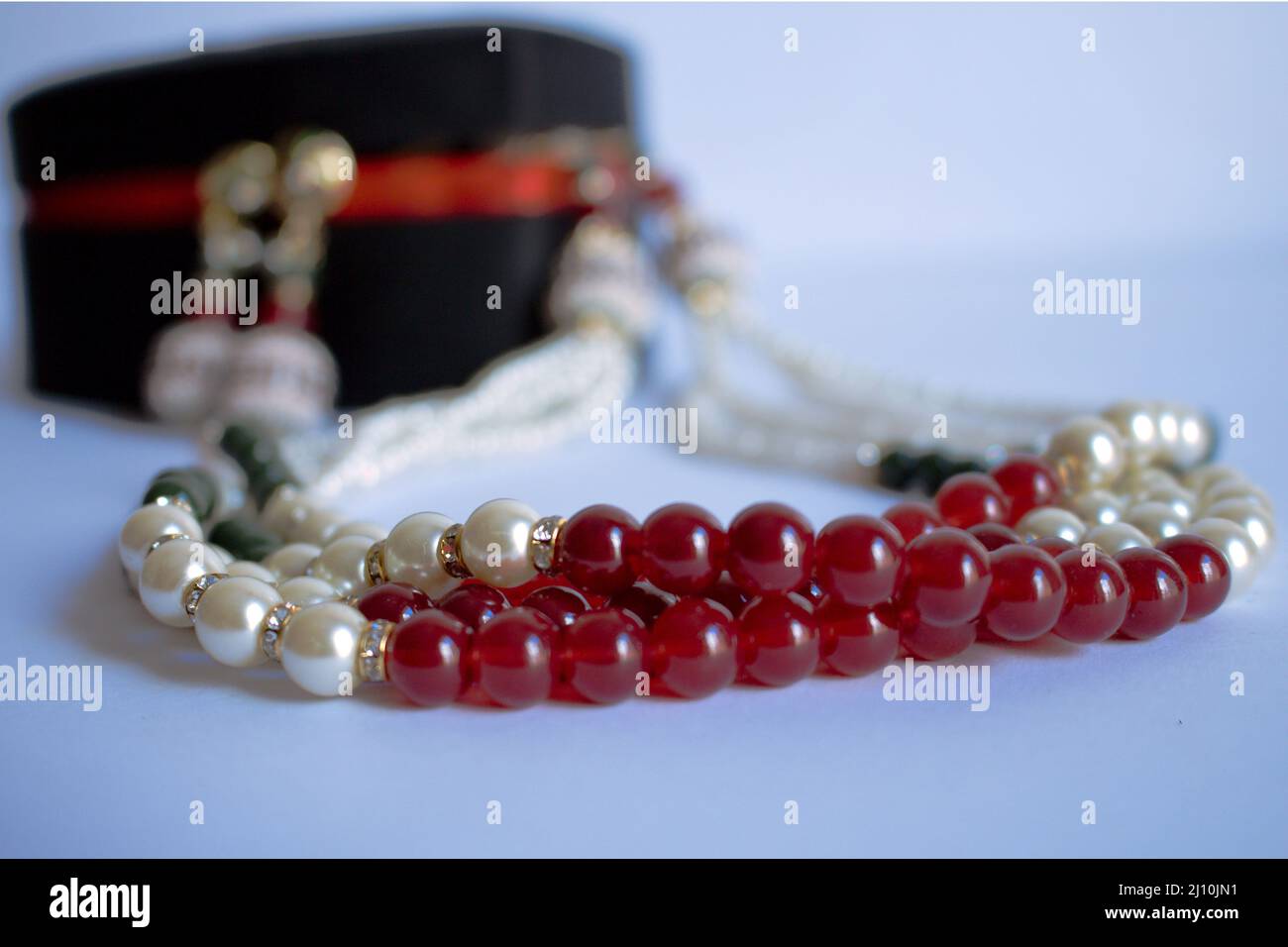 Una collana in perla in una scatola di gioielli che è metà all'esterno con uno sfondo bianco e fuoco selettivo Foto Stock