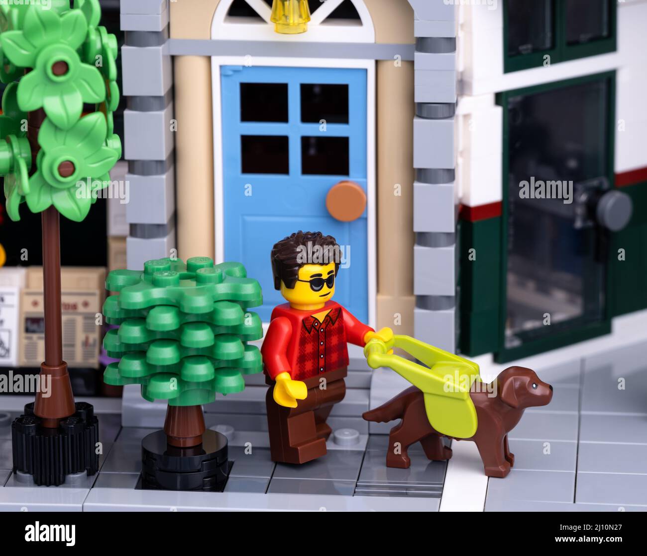 Tambov, Federazione Russa - 08 gennaio 2022 una minipfigura uomo per non vedenti Lego con un cane guida che lascia la casa con la porta blu e il walkin Foto Stock