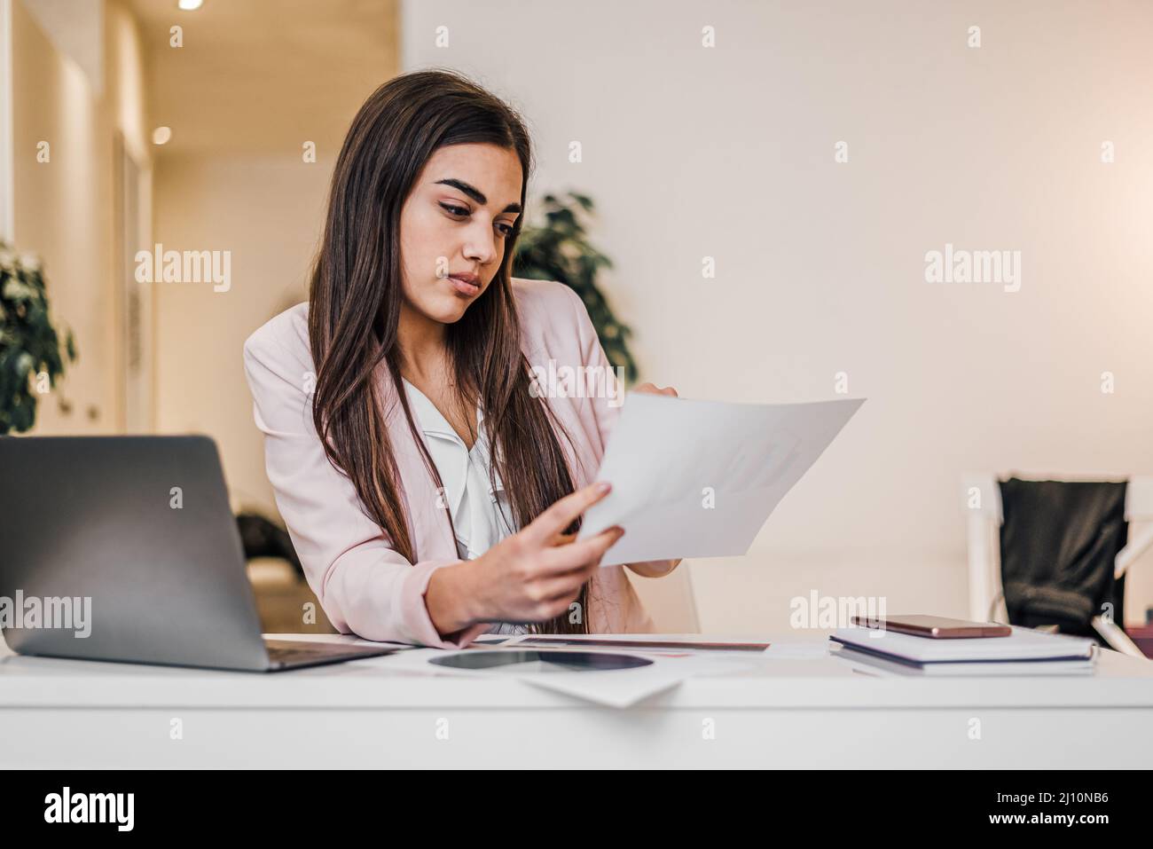 Occupato giovane commercialista femminile. Leggere un documento nel suo ufficio aziendale. Foto Stock