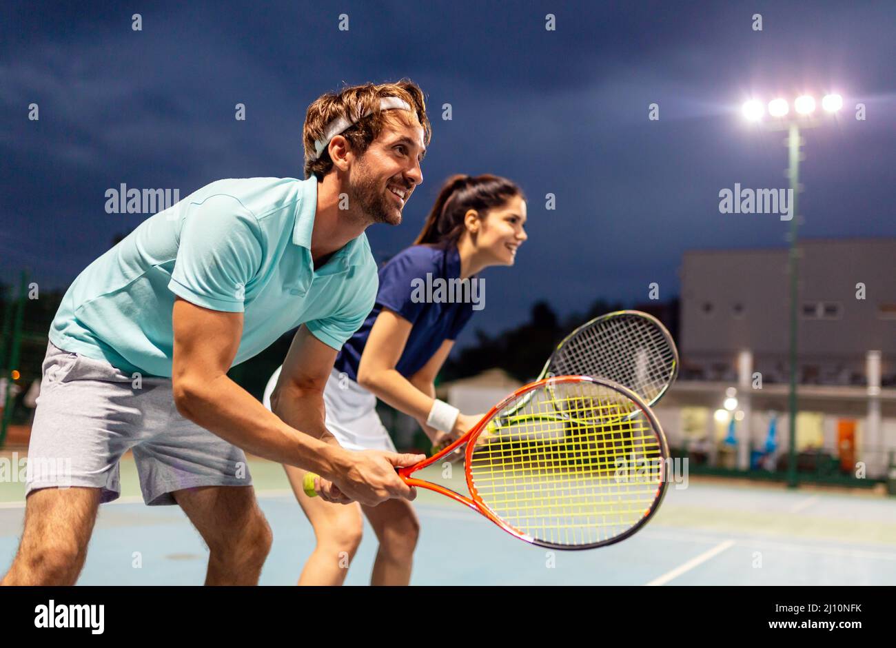 Concetto di persone di sport di tennis. Giocatore doppio misto che colpisce la palla da tennis con il partner in piedi vicino alla rete Foto Stock