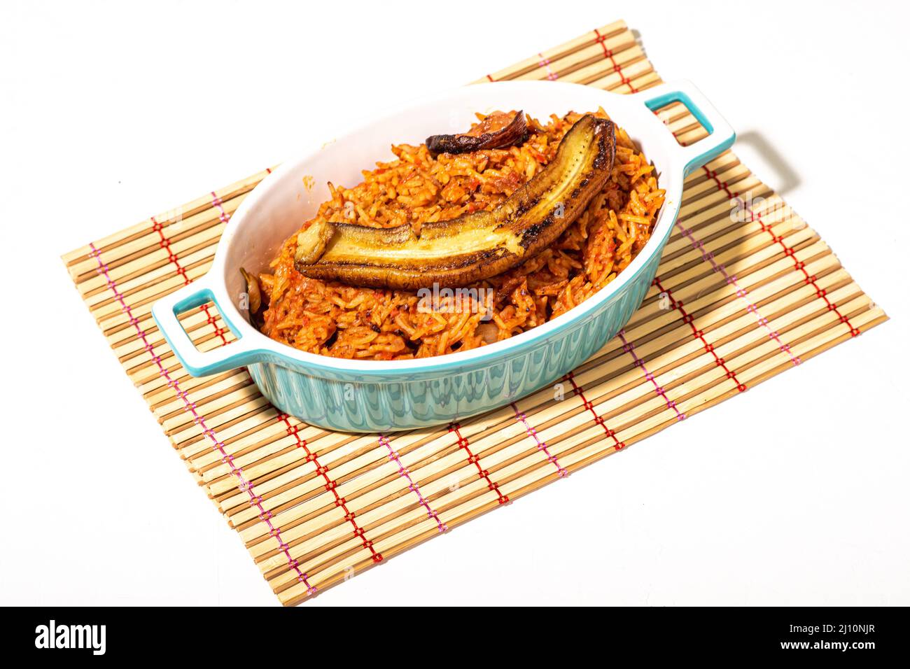 Jollof riso con banana fritta. Riso tipico nigeriano con pomodori, cipolle e spezie. Sfondo chiaro. Foto Stock