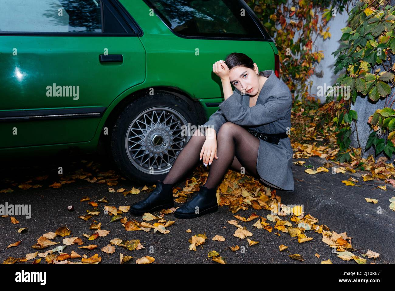 Donna seduta accanto ad una macchina verde Foto Stock