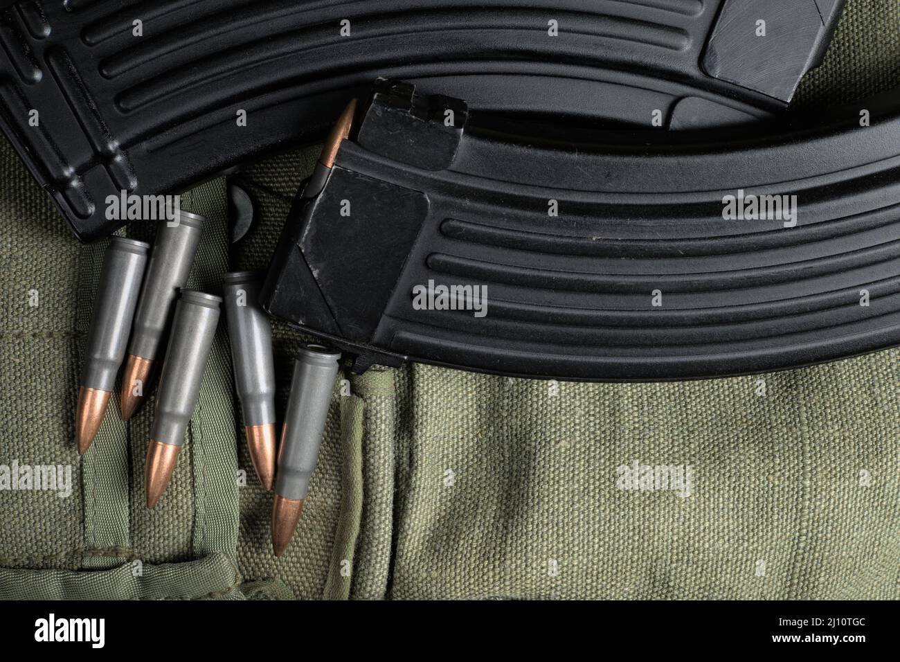 AK-47 (7,62x39mm) munizioni e 2 riviste giacenti su un pezzo di tela militare Foto Stock