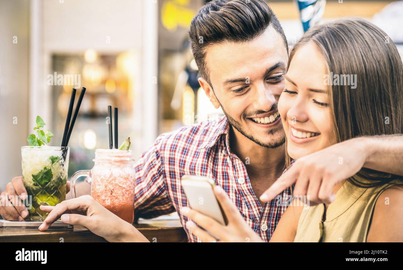 Giovane coppia di amanti della moda che giocano con smartphone mobile al cocktail bar - rapporto amore concetto con felice ragazzo e ragazza togetel Foto Stock